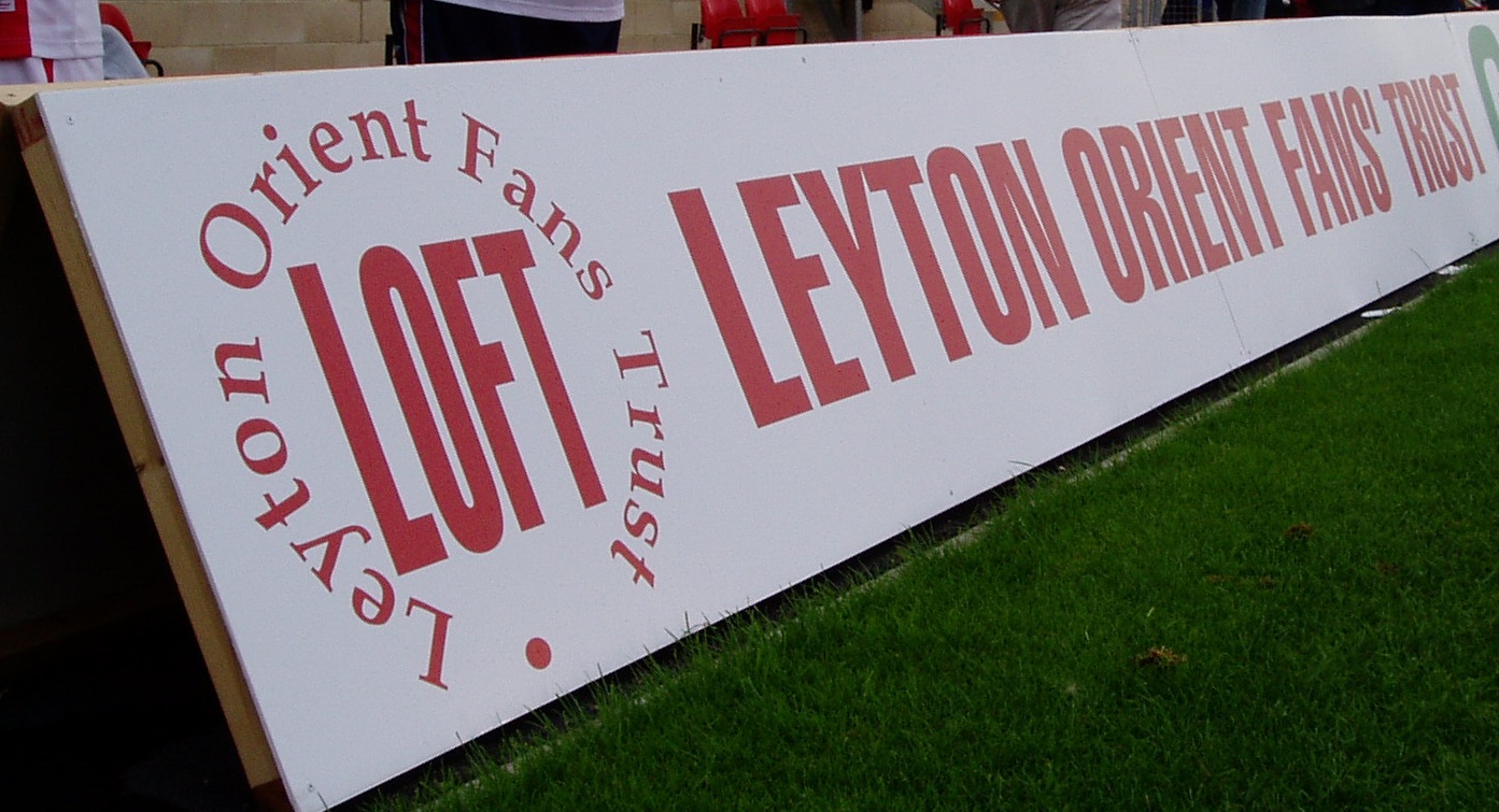 A white hoarding with the logo of LOFT and the words LEYTON ORIENT FANS' TRUST